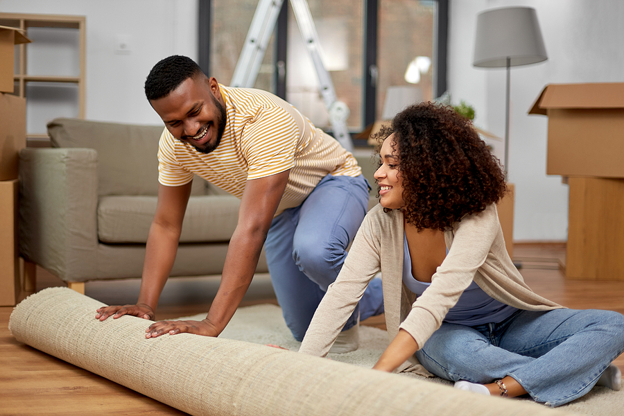 Stock Photo - couple unrolling carpet in living room